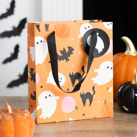 An orange gift bag with a Halloween theme, featuring ghosts and pumpkins, with a black handle.