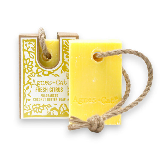 Yellow soap bar with a rope and packaging labeled 'Agnes + Cat' on a white background