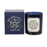 A dark blue scented candle in a glass jar next to its matching dark blue box. The packaging and label feature a white pentagram surrounded by a floral wreath, with the scent name 'Snooky Amber & Vanilla' printed on the box.