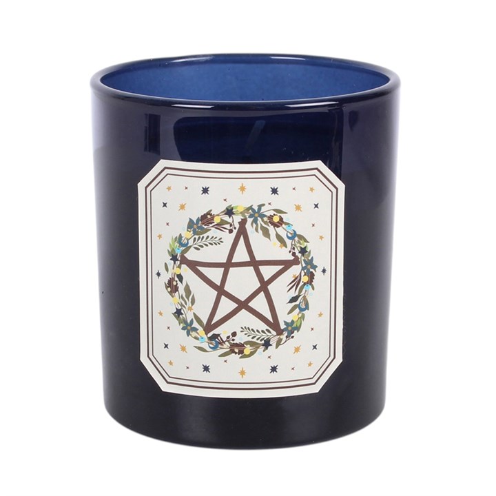 A dark navy blue ceramic candle jar with a glossy finish, featuring a white decorative label on the front with a brown pentagram surrounded by a floral wreath.