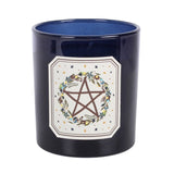 A dark navy blue ceramic candle jar with a glossy finish, featuring a white decorative label on the front with a brown pentagram surrounded by a floral wreath.