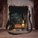 Black crossbody bag with a cat and candle design on a wooden surface
