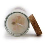 Candle with pink crystals in a glass jar with a cork lid on a white background