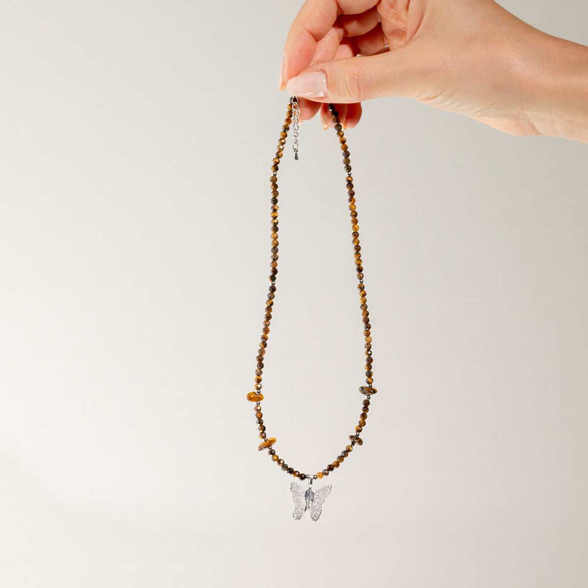 Tiger's Eye gemstone necklace held up showing full length and butterfly pendant
