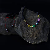 Colorful beaded bracelet on a dark stone surface with a black background