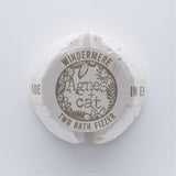 Round bath fizzer with 'Agnes + Cat' branding on a light gray background