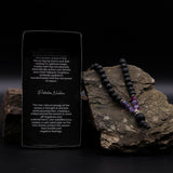 Necklace with beads on a rock next to an information card on a dark background