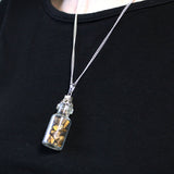 Necklace with a small bottle pendant containing gold-colored stones on a black background