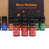 Set of Christmas-themed fragrance oil bottles with colorful labels on a white surface.