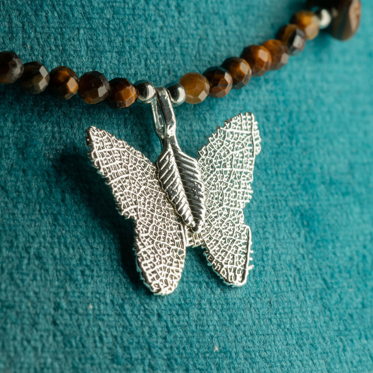 Close-up of real leaf butterfly pendant with golden-brown Tiger's Eye beads