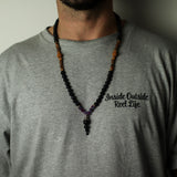 Person wearing a gray shirt with a necklace and 'Inside Outside Reel Life' text.