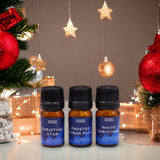 Three essential oil bottles labeled 'Christmas Star', 'Frosted Sugar Plum', and 'White Christmas' with Christmas decorations in the background.