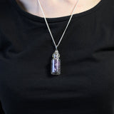 Necklace with a small glass bottle pendant on a black shirt