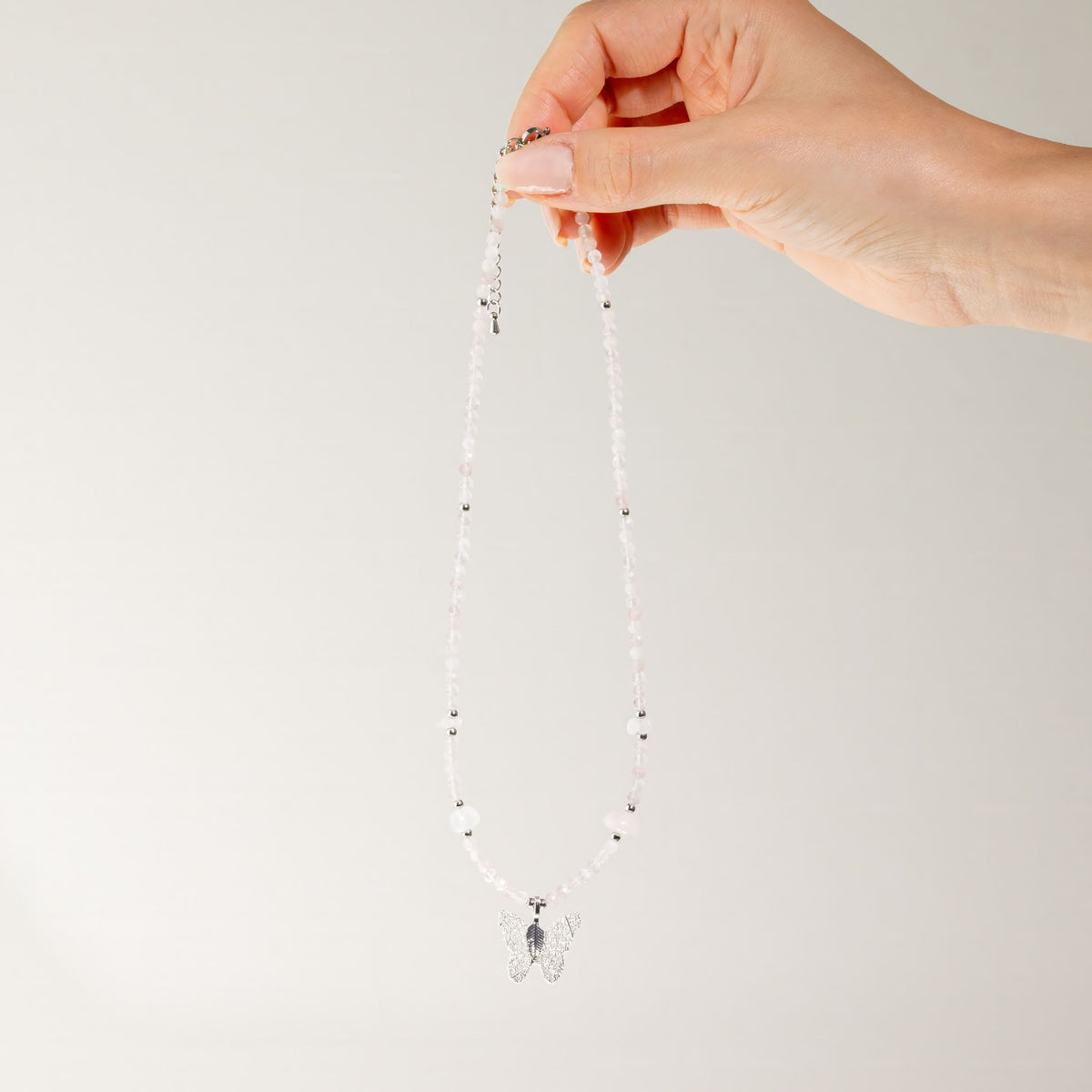 Rose Quartz gemstone necklace held up showing full length and butterfly pendant