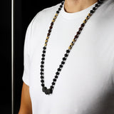 Person wearing a long beaded necklace on a plain background