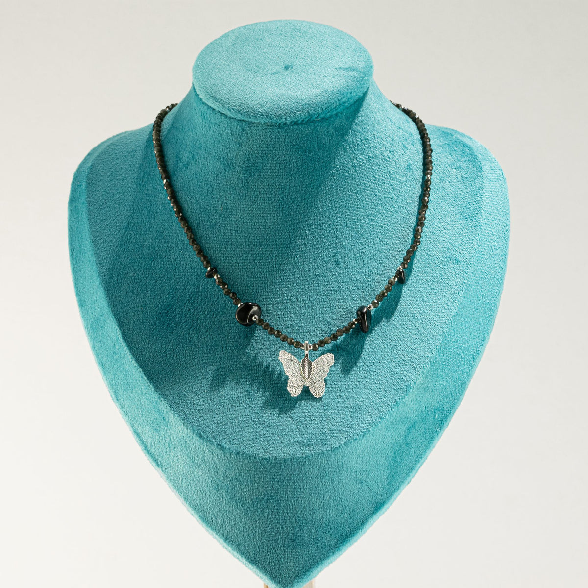 Black Obsidian butterfly necklace displayed on turquoise jewellery bust