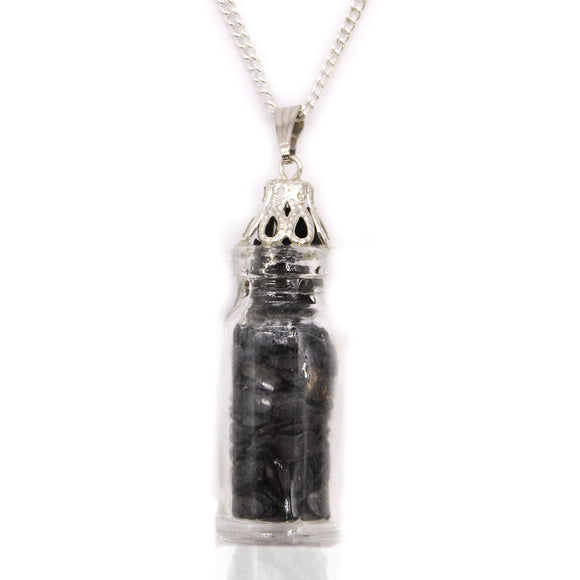 Silver pendant with a clear container holding black stones on a white background