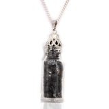 Silver pendant with a clear container holding black stones on a white background