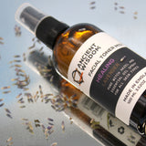 Bottle of Ancient Wisdom facial toner mist with lavender flowers on a reflective surface