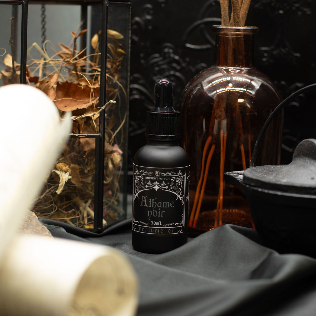Perfume bottle labeled 'Athame Noir' with decorative elements on a dark background
