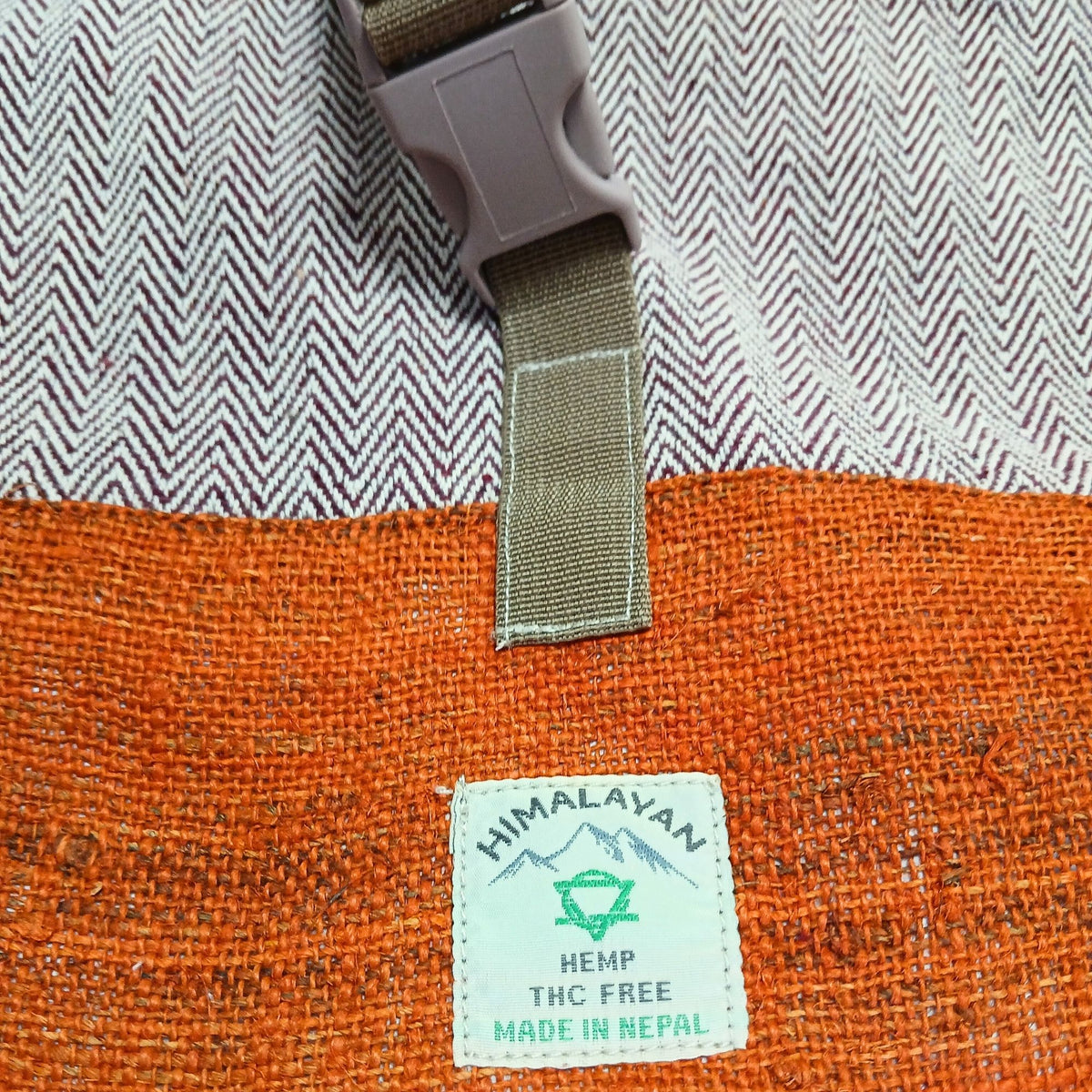 Close-up of sunset orange hemp backpack showing buckle fastening and woven fabric