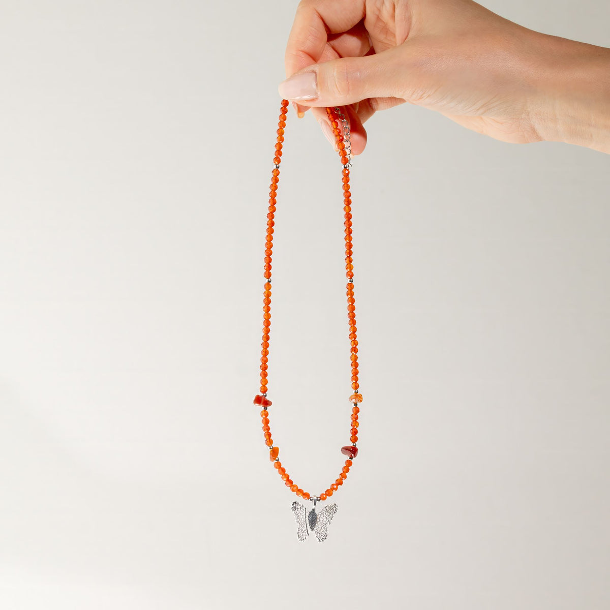 Red Ruby gemstone butterfly necklace held up to show full length