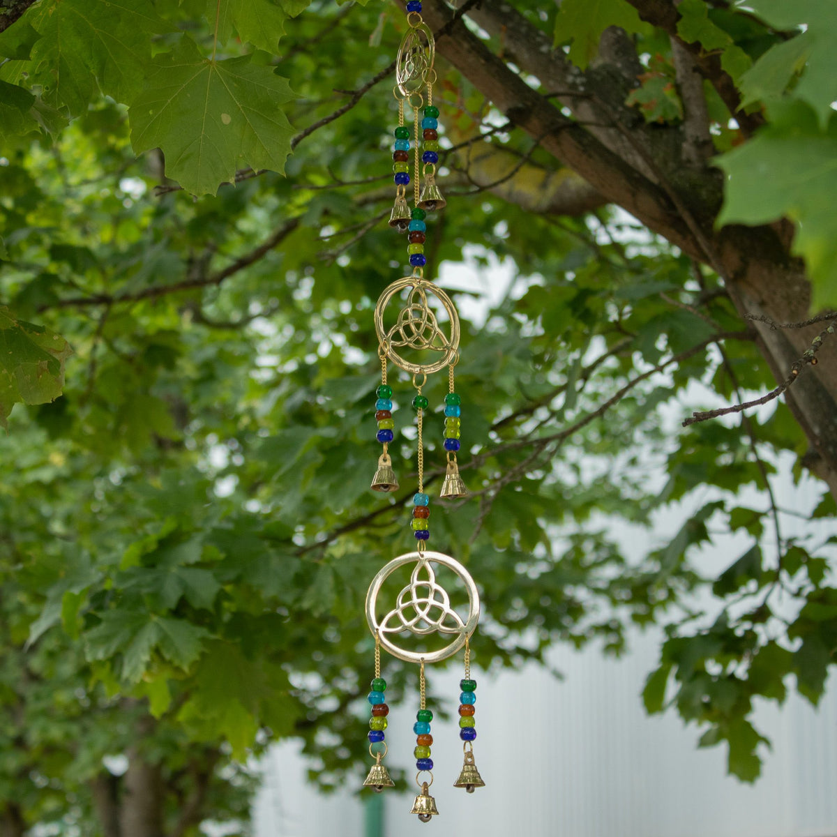 1. Celtic wind chimes with seven bells hanging from a leafy tree