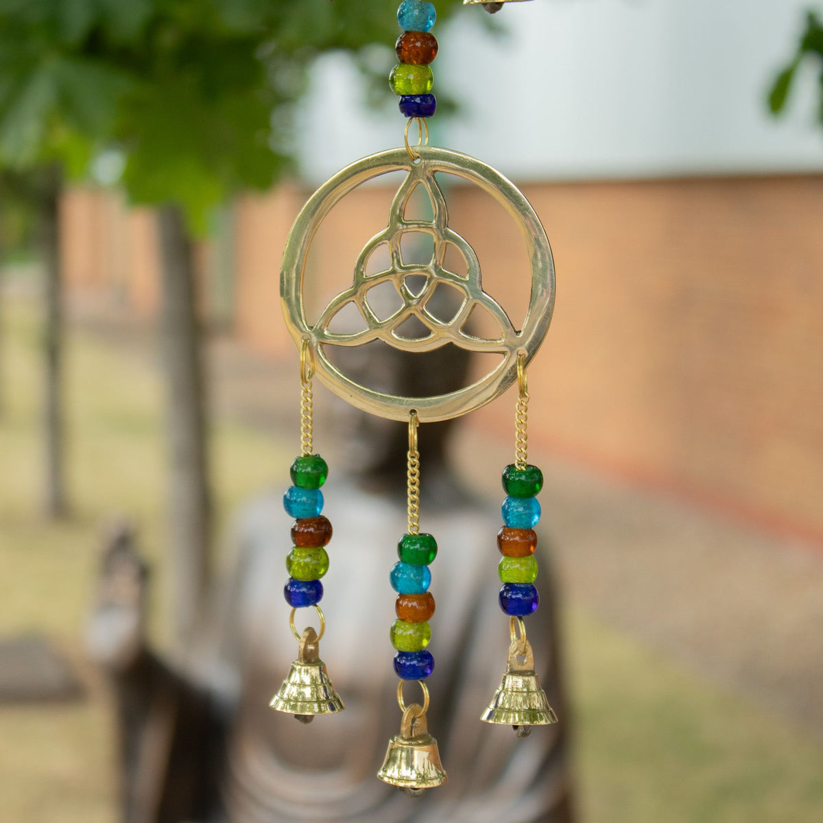 Close-up of Celtic knot wind chimes with brass bells and multicoloured beads