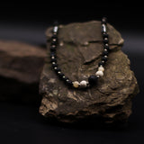 Necklace with black and beige beads on a textured stone surface