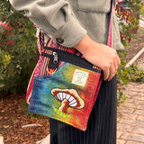 Colorful handbag with mushroom design held by a person outdoors