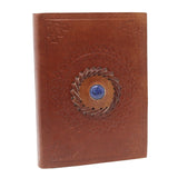 Brown leather notebook with decorative emblem and blue gemstone on a white background