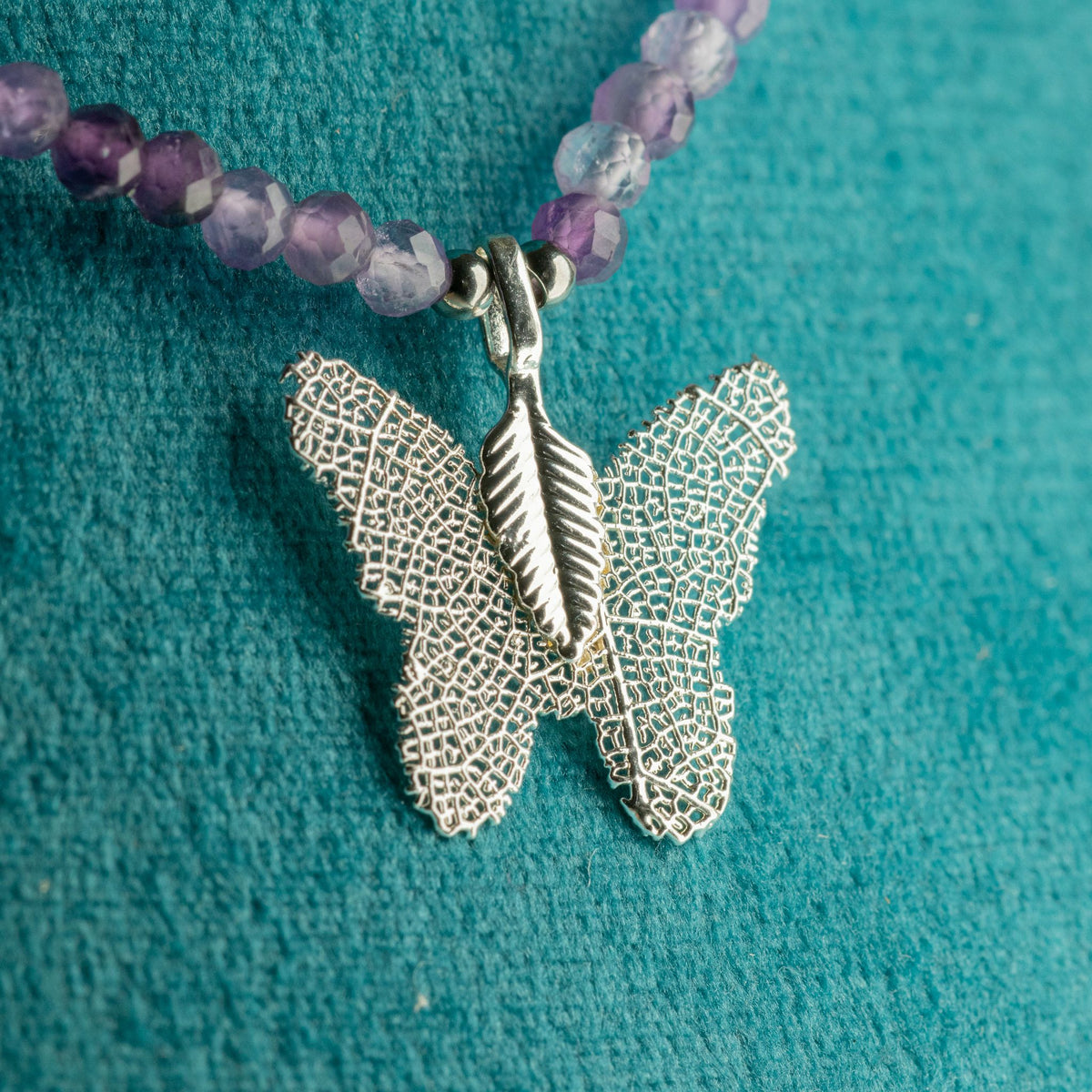 Close-up of silver-plated real leaf butterfly pendant and amethyst beads