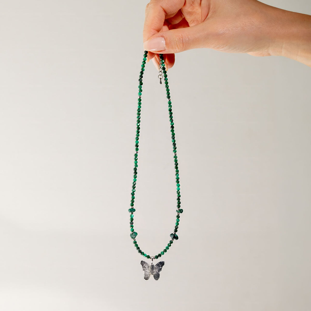 Green Malachite gemstone necklace held up showing full length and butterfly pendant