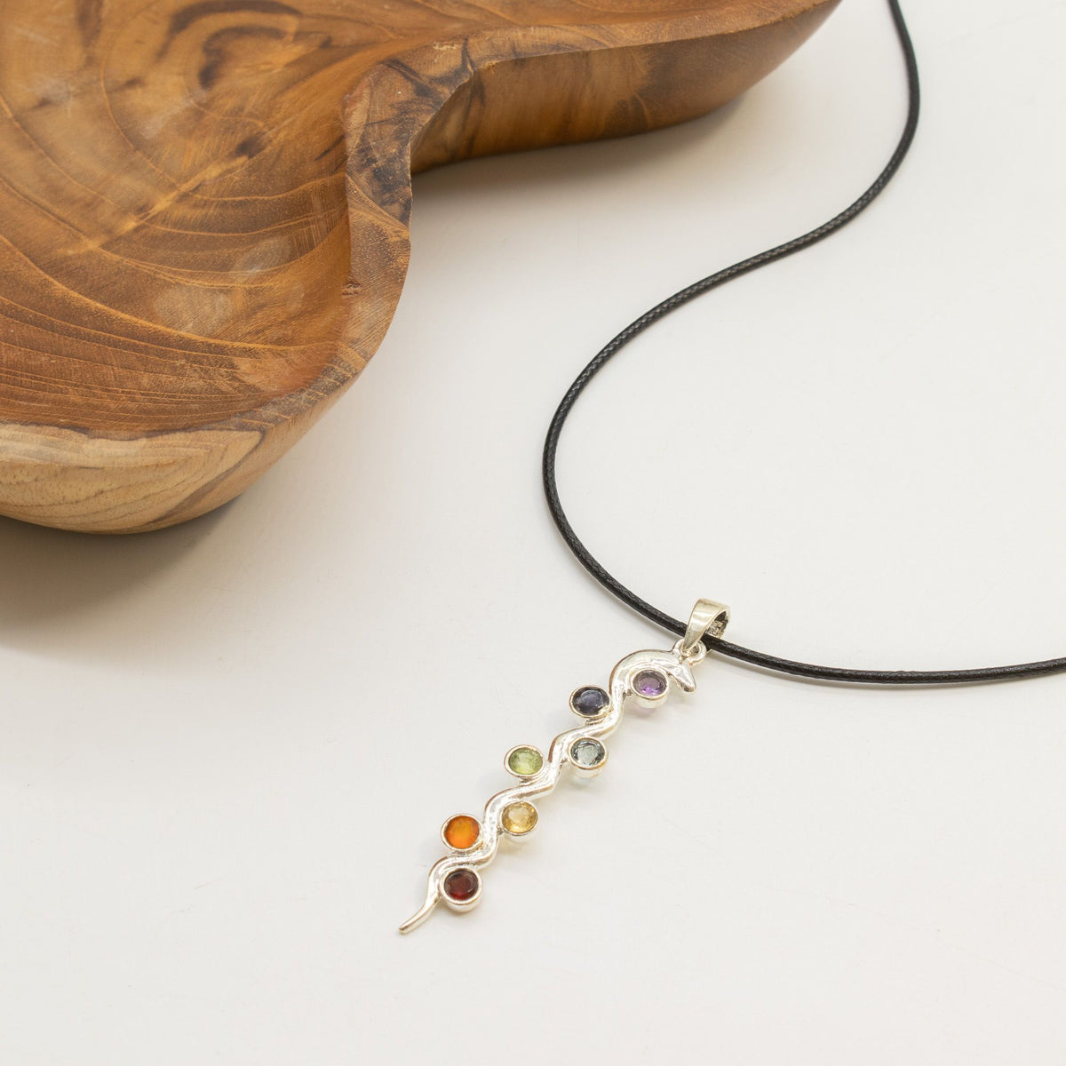 Snake chakra necklace displayed beside wooden ornament