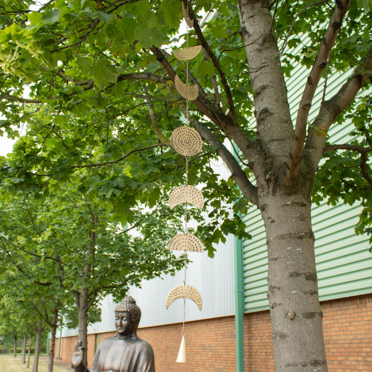 Brass Moon Phases wind chime hanging from a tree