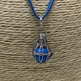 Blue pendant necklace with silver cage on a textured beige background