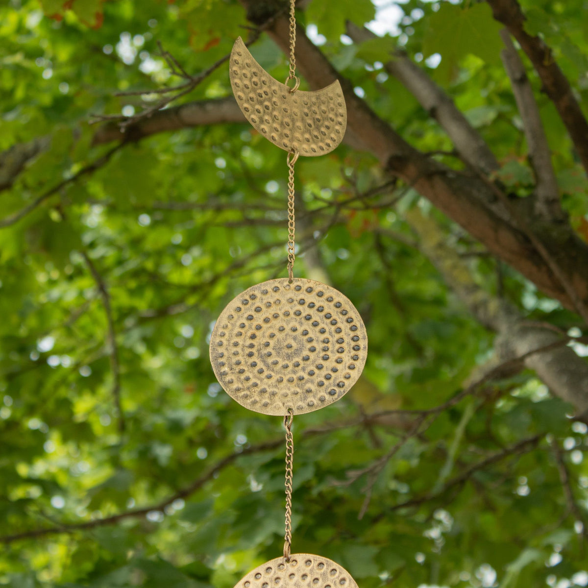 Detailed brass moon phase ornaments hanging outdoors