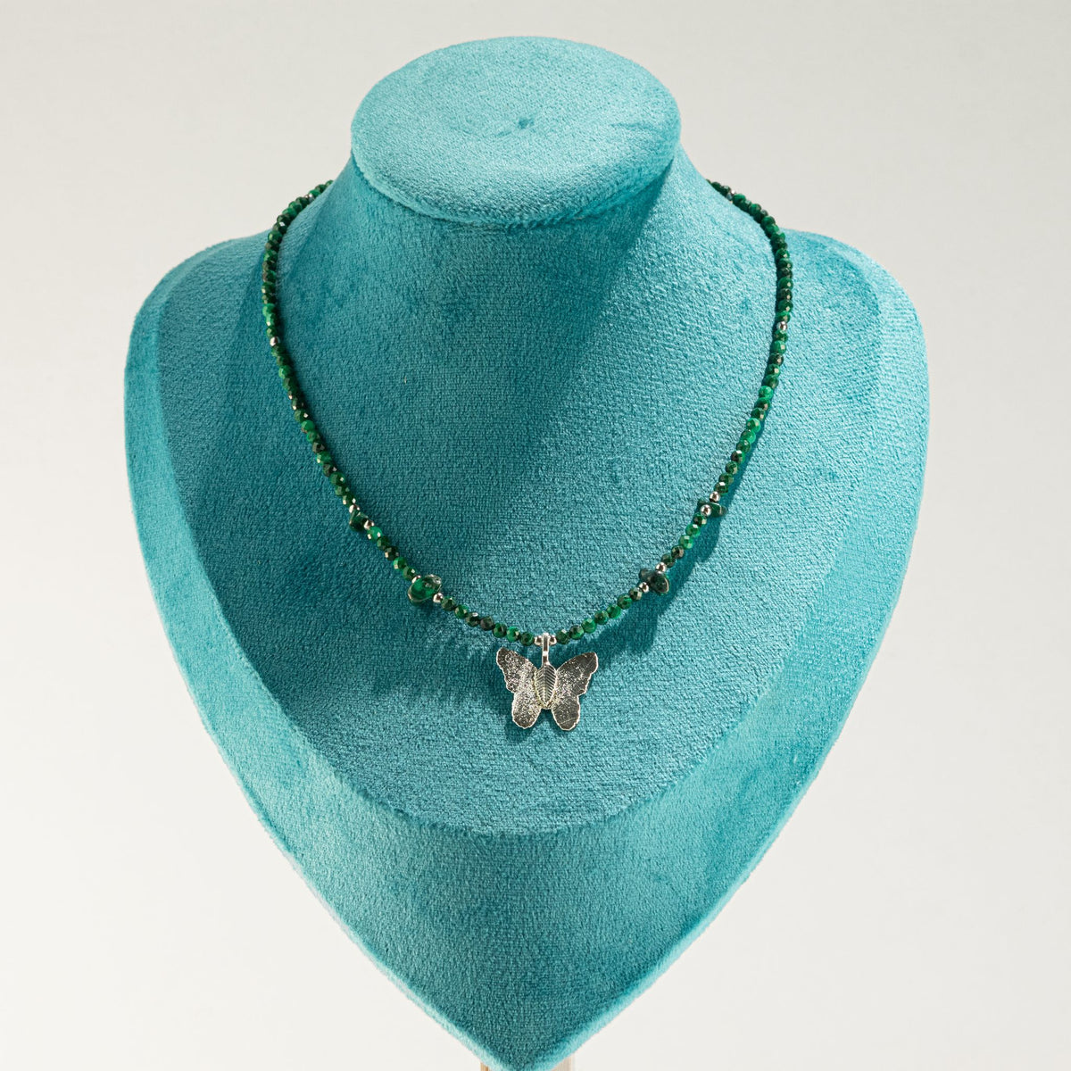 Malachite butterfly necklace displayed on turquoise jewellery bust