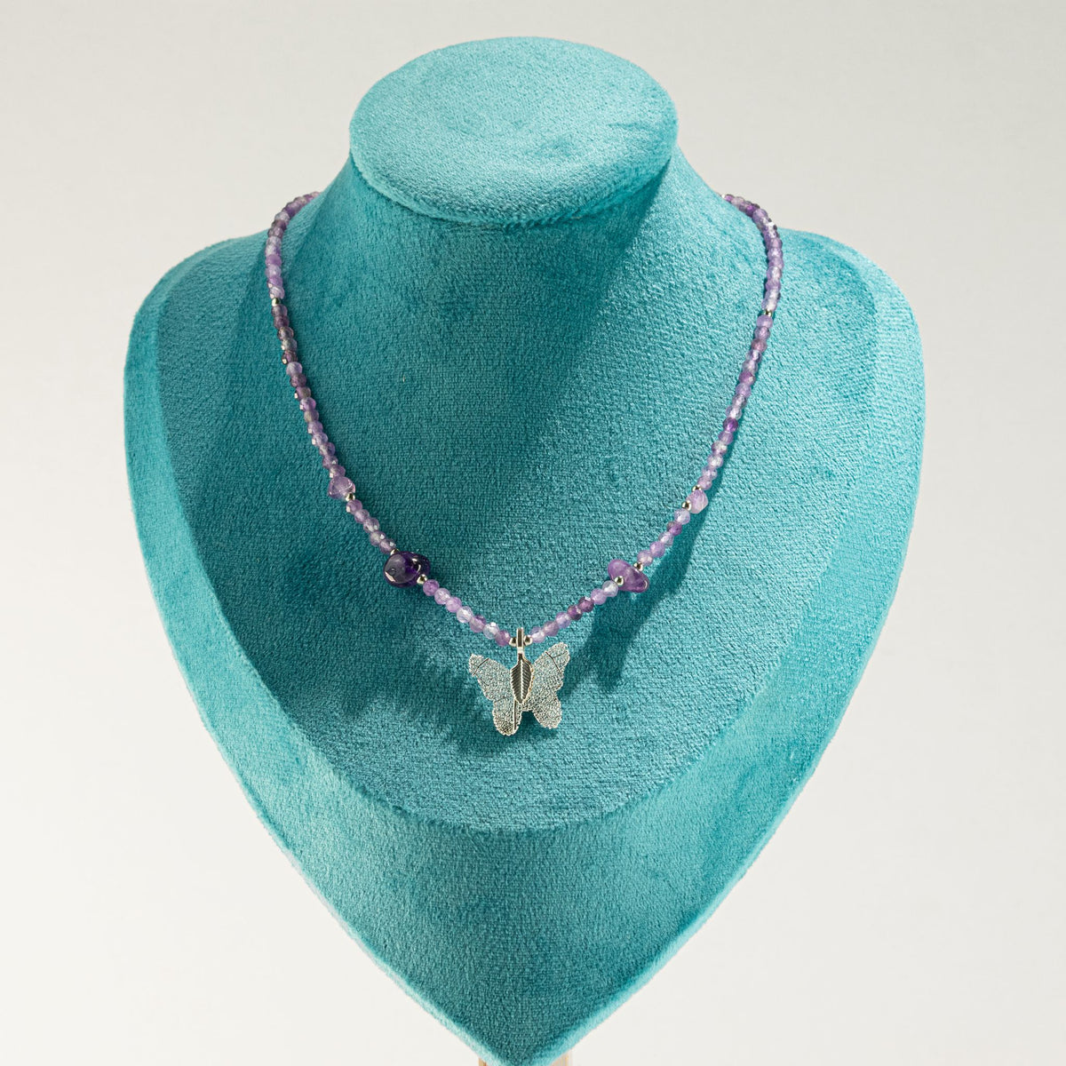 Amethyst butterfly pendant necklace displayed on turquoise jewellery bust