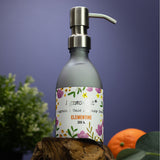 Bottle of Agnes & Daphne Clementine hand cream with a floral label on a wooden surface against a purple background.