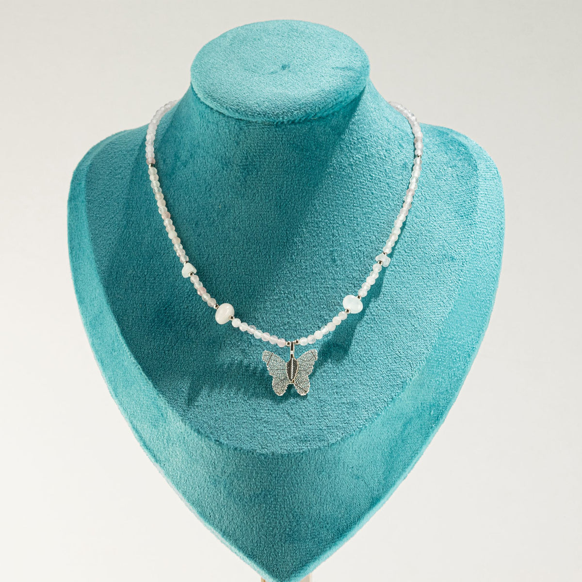 Rose Quartz butterfly pendant necklace displayed on turquoise jewellery bust