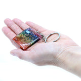 Hand holding a colorful keychain with a design on a white background