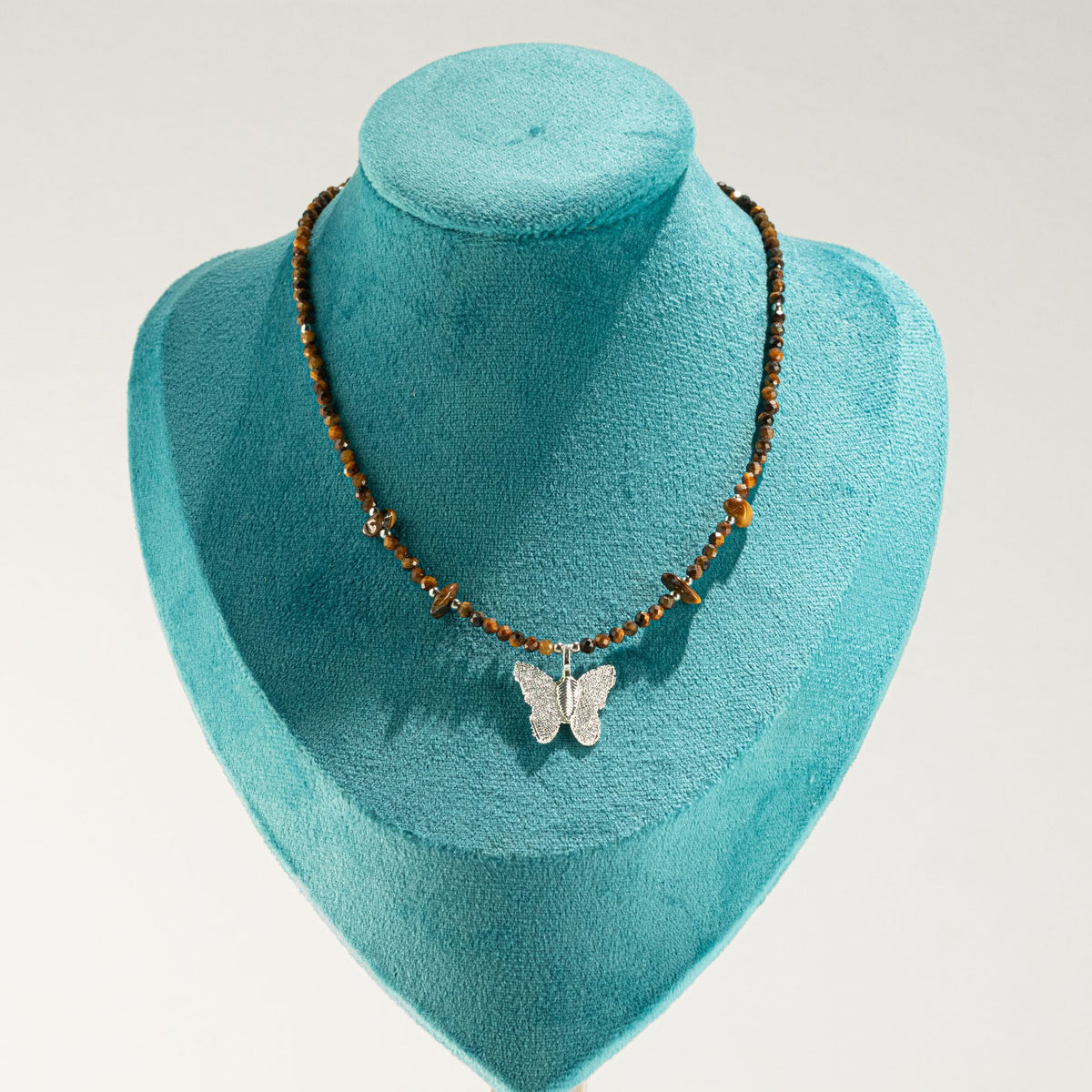 Tiger's Eye butterfly necklace displayed on turquoise jewellery bust