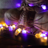 Decorative string lights wrapped around a wooden sculpture with a blurred background