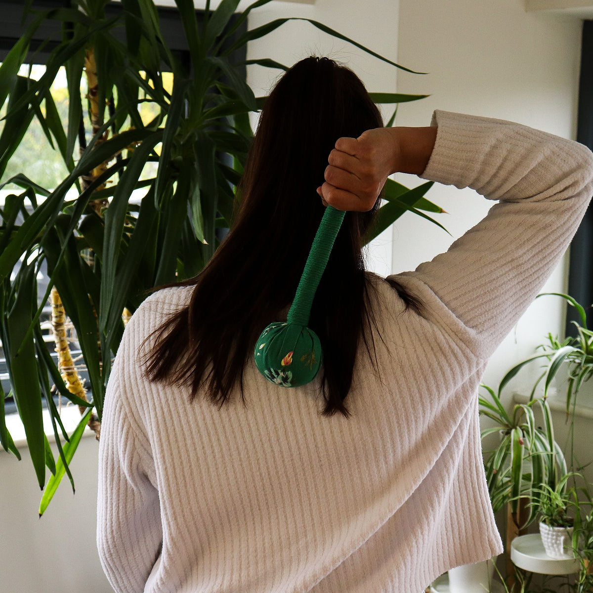 Green wormwood massage hammer being used on shoulder