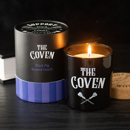 Candle labeled 'The Coven' with packaging on a dark surface