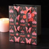 Gift bag with pink floral and butterfly design on a dark background