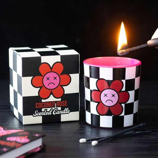 Candle with checkered packaging featuring a flower design, being lit with a match.