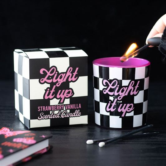 Checkered candle with 'Light it up' text and a matching box on a dark surface.