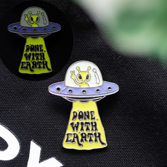 Glow in the dark UFO enamel pin badge on black fabric